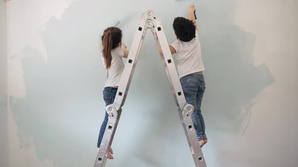 Caucasian Boy and Girl Paint the Wall with Rollers Standing on a Stepladder Brother and Sister Paint