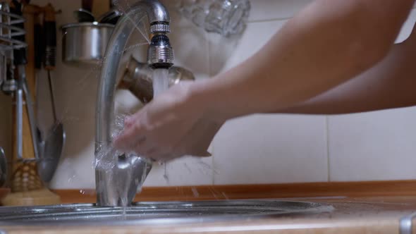 Female Hand Opens and Closes Leaking Water Tap alt
