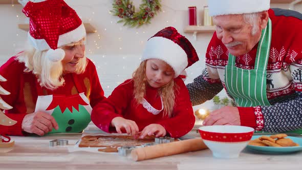 Senior Family Grandparents with Granddaughter in Santa Claus Hats Preparing Cooking Homemade Cookie alt