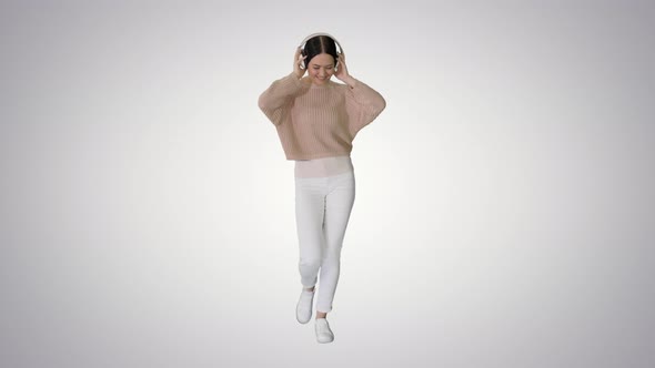 Smiling Female with Headphones Walking and Dancing To the Music on Gradient Background alt