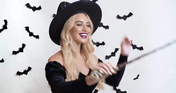 Halloween Is Coming. Young Lady in Enchantress Costume Conjuring with Magic Wand and Smiling alt