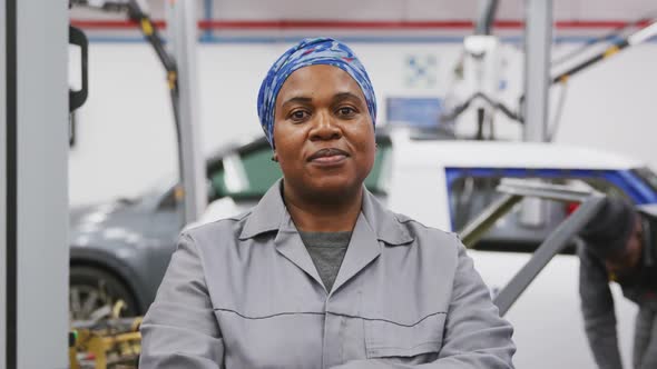African American female car mechanic crossing her arms and looking at camera alt