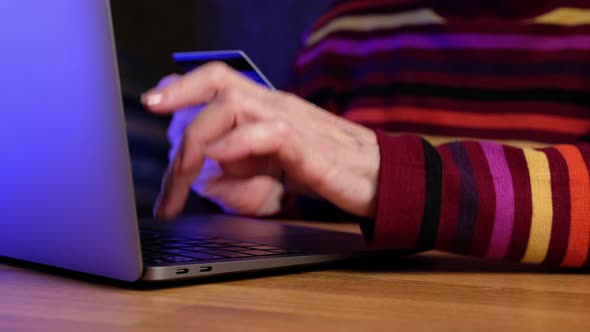 Modern Elderly Retired Woman Makes Purchases Online Using Credit Card on Laptop