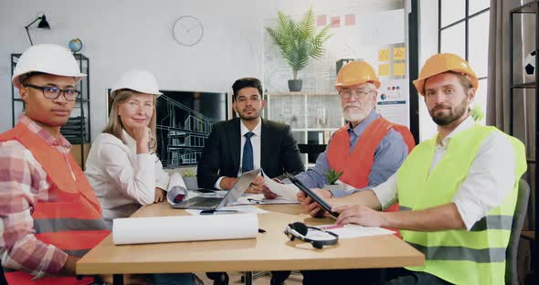 Multiethnic Team of Engineers with Foreman which Sitting in front of Camera in Meeting Room alt