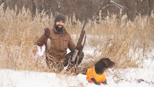 Tired Hunter and His Dog Having a Rest on a Cold Winter Day alt