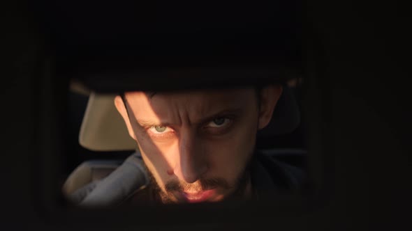 Man Looks at Himself in a Mirror While Sitting in a Car alt