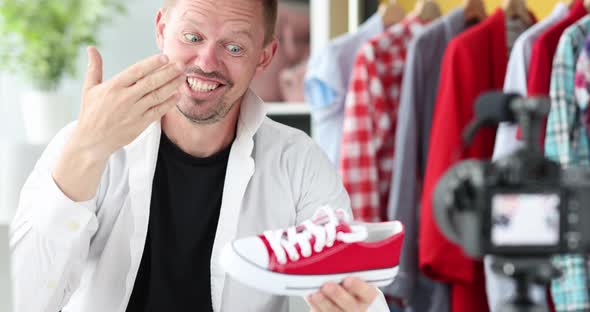 Enthusiastic Male Blogger Demonstrates Red Sneakers to Camera  Movie alt