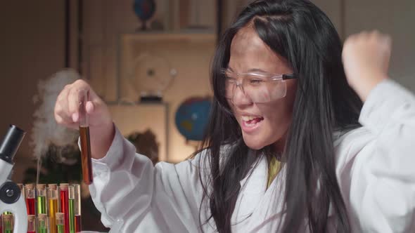 Excited Young Asian Scientist Girl With Dirty Face Mixes Chemicals In Test Tube alt