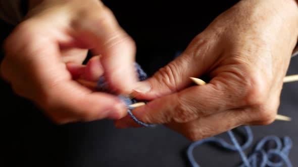 Elderly woman is knitting socks with four needles, close up