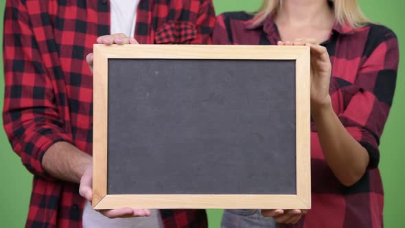 Young Couple Holding Blackboard Together