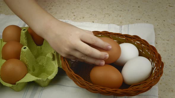 Closeup of a Child's Hand Transferring Eggs From a Container to a Basket