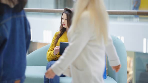 Woman Sitting in Mall and Using Tablet alt