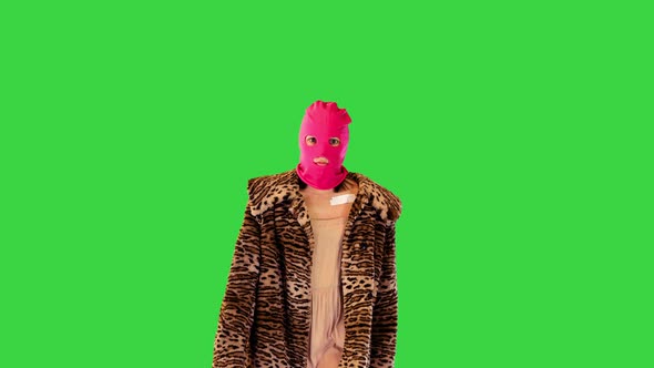 Caucasian Girl in Pink Balaclava and Faux Fur Coat Walks Looking Confident on a Green Screen Chroma
