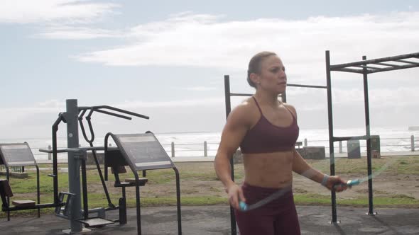 Sporty Caucasian woman exercising in an outdoor gym during daytime alt