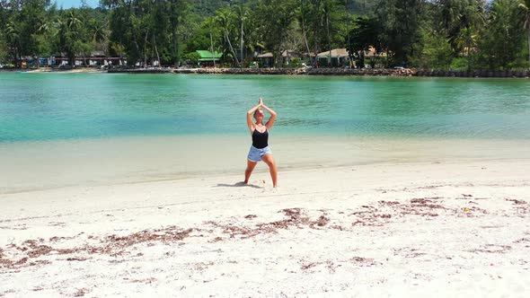 Blonde attractive caucasian woman relaxing on the sandy beach practicing yoga on summer vacation. Me alt