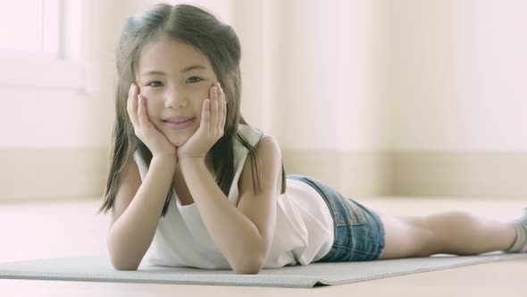 Portrait of a cute little Asian girl lying down on the floor alt