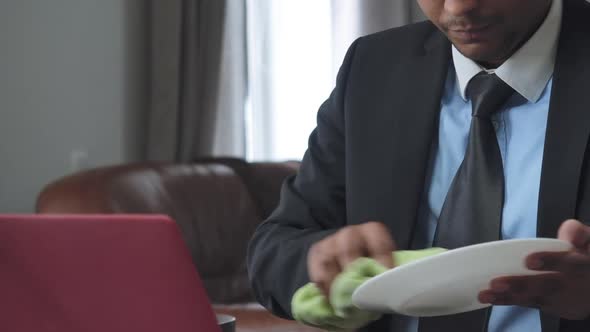 Young Unrecognizable African American Man in Headphones and Formal Suit Cleaning Plate Talking in alt