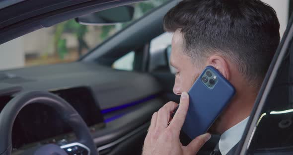 Businessman Talking on Mobile While Choosing Car at Salon
