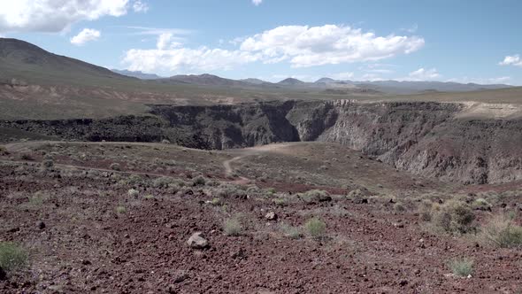 Porous volcanic red rock landscape and canyon in Death Valley, California, Aerial low flyover shot alt
