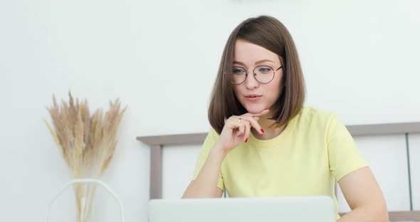 Young Beautiful Woman is Communicating Sittting on the Bed in Front of a Laptop alt