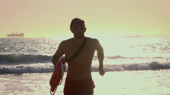 Male lifeguard running along the beach alt