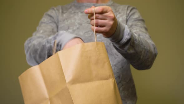 Man Taking Glass Eco Bottle with Clear Water From Paper Bag