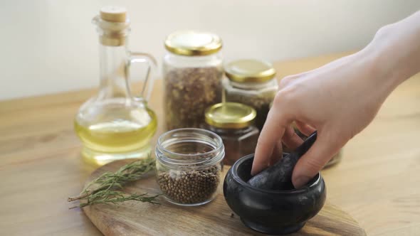 Woman's Hand Mixes and Crushes Coriander Seeds By Granite Mortar with Pestle in Slow Motion alt