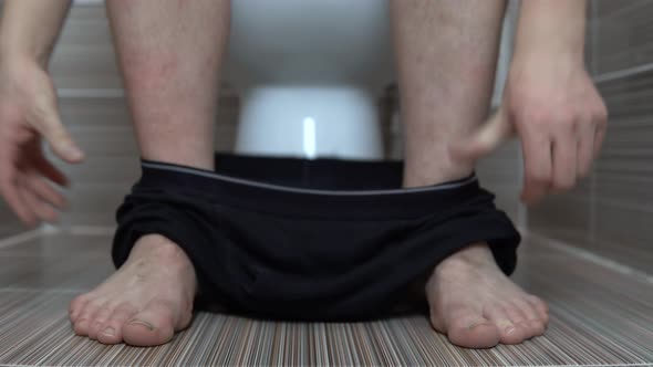 The Man Took Off His Black Panties While Sitting on the Toilet. A Man with Hairy Legs in the Toilet alt