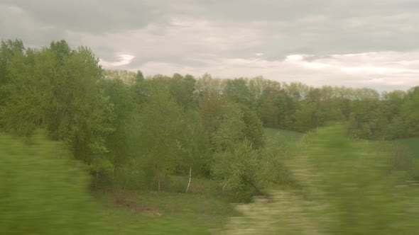 View From Window of Highspeed Train on Landscape of Beautiful Nature Wild Field and Forest on