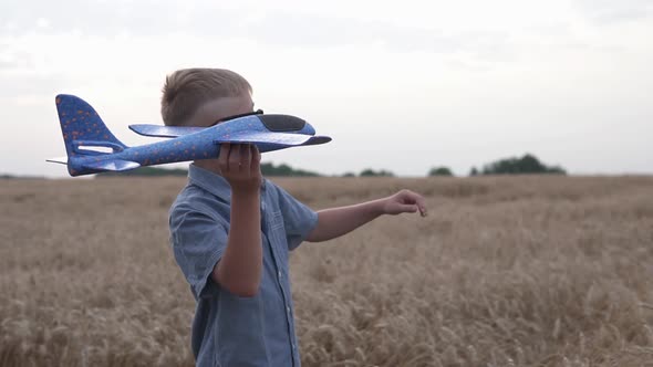 Happy guy with a toy airplane on a wheat field in the sunset light. alt