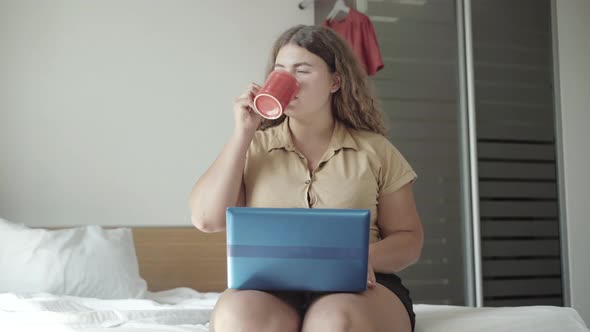 Confident Young Plus-size Woman Checking E-mail in the Morning and Drinking Coffee. Portrait of alt