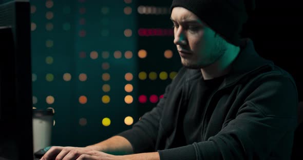 Concentrated and Anxious Hacker Wearing a Sweatshirt and Cap Breaking Into Corporate Data Servers alt