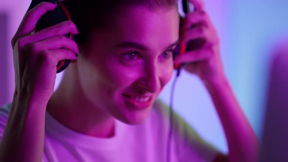 Cyber Girl Put Headphones in Pink Neon Lights Closeup alt