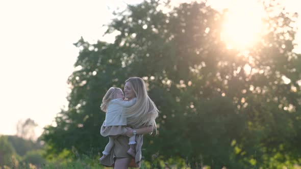 Young Loving mum and baby playing together outdoor enjoy beautiful sunset in the field.