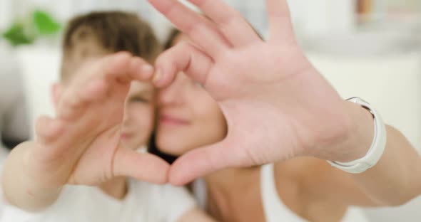 Young Beautiful Mother and Her Teen Son Showing Heart Shape with Their Fingers