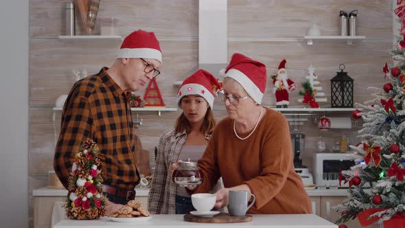 Grandfather Serving Child with Baked Delicious Cookie While Grandmother Putting Coffee alt