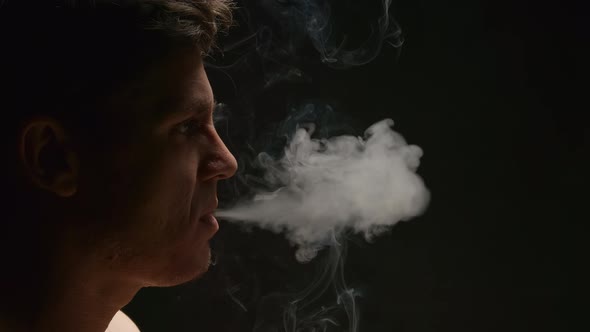 Smoker exhales out a smoke