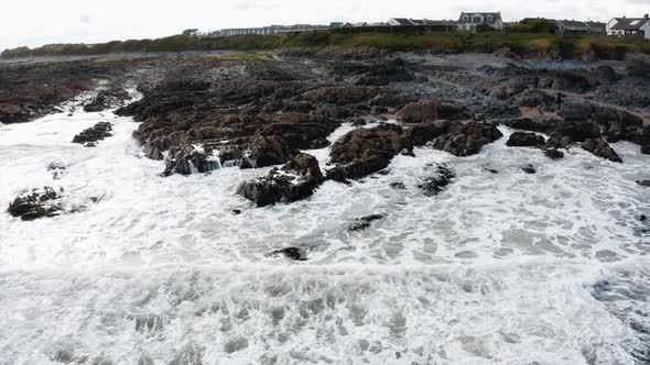 The rocky beach in Skerries, Ireland. The view of strong waves crashing into the rocky shore. alt