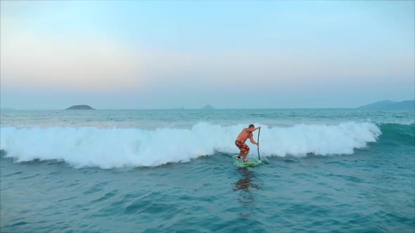 Surfer Flies on the Crest of a Wave, a Surfer Controls the Oar, Standing on a Surfboard. Surfer Is alt