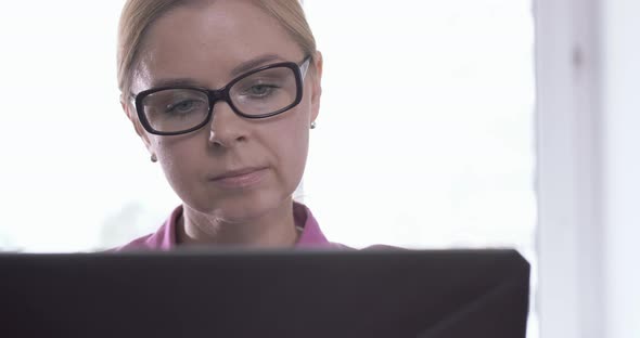 Portrait of Smiling Woman Wearing Glasses Working at Home with a Laptop