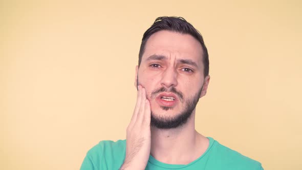 Young Man with Helpless Face in Pain From Toothache Holding Hand Against His Cheek alt