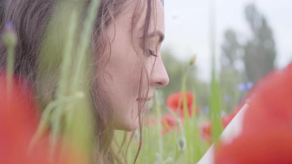 Portrait of Cute Adorable Woman Sitting in Poppy Field Reading Book Outdoors alt