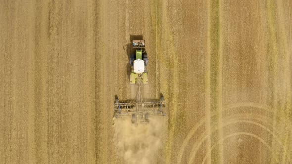 Tractor plows ground on cultivated farm field.  alt