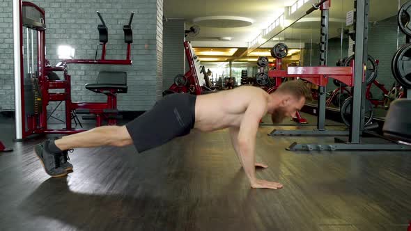 Athlete with Toned Body Doing a Jump Pushup in an Indoor Gym alt