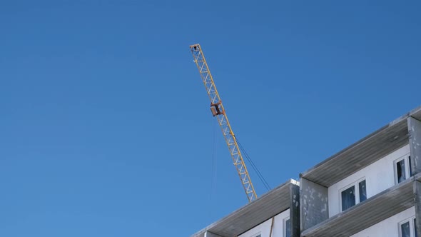 Construction of a Multi-storey Building. Crane Turns To the Side Over the Roof.