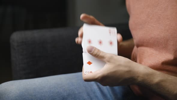 Long shot from side of male hands shuffling and dropping playing cards alt