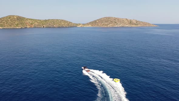 Aerial View of a Motor Boat Towing a Tube. Elounda, Crete, Greece