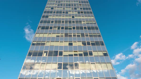 Modern office building and clouds in reflection, time-lapse alt