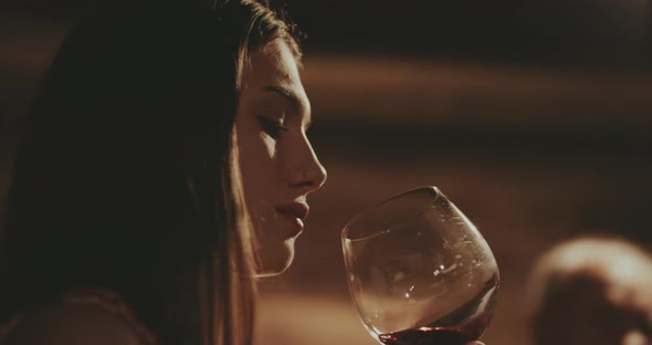 Young woman swirling red wine in her glass then she is taking a sip alt