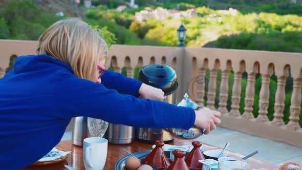 Blonde tourist girl having typical moroccan breakfast in High Atlas mountains alt